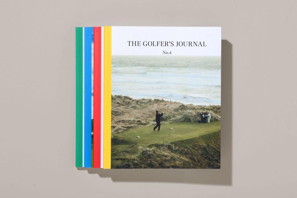 Issues of The Golfer's Journal stacked on a grey background