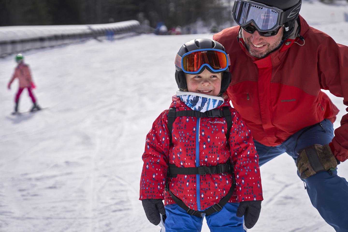 Smiling child skier with her father at saskadena six learning area