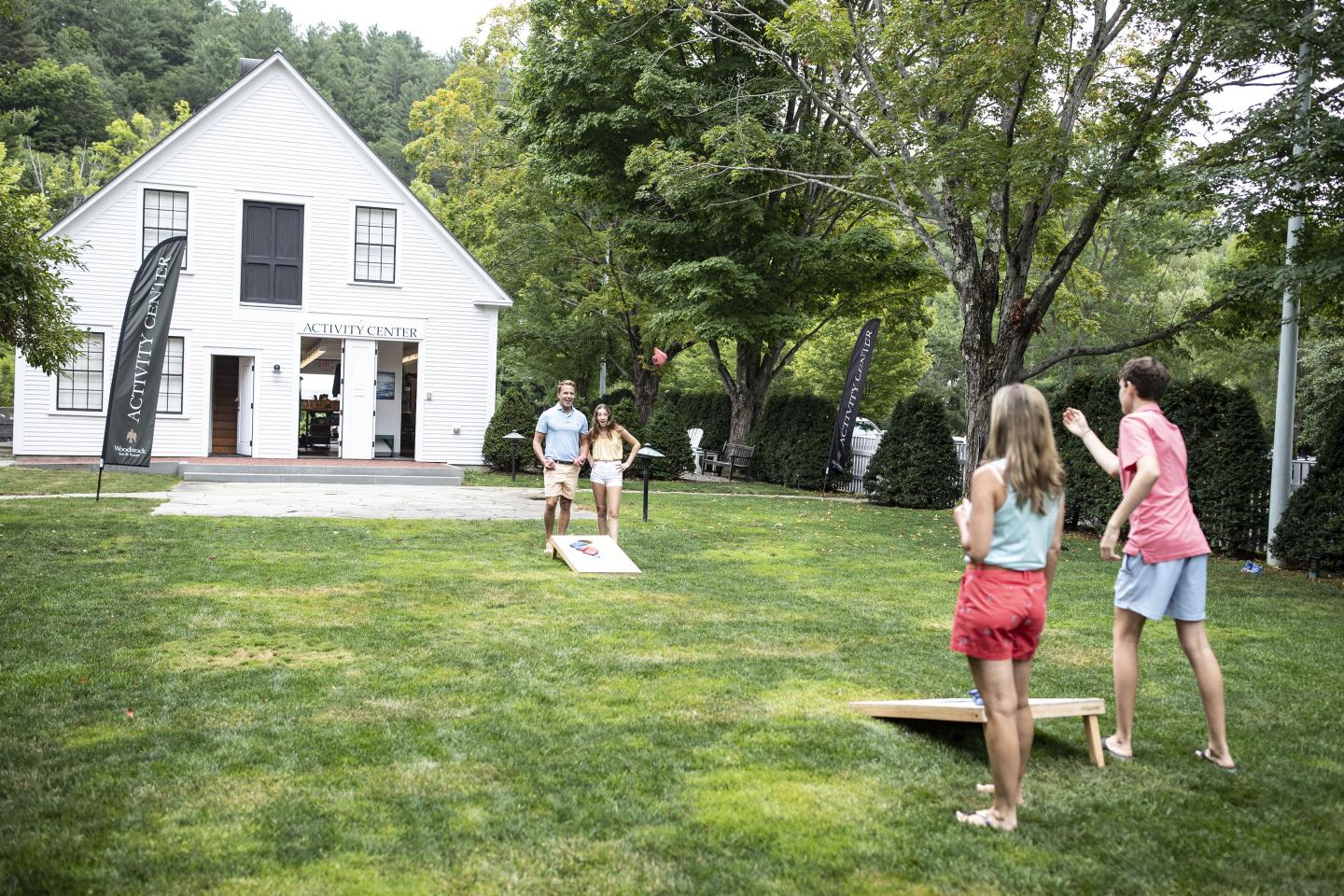 family plays cornhole on the activity center lawn