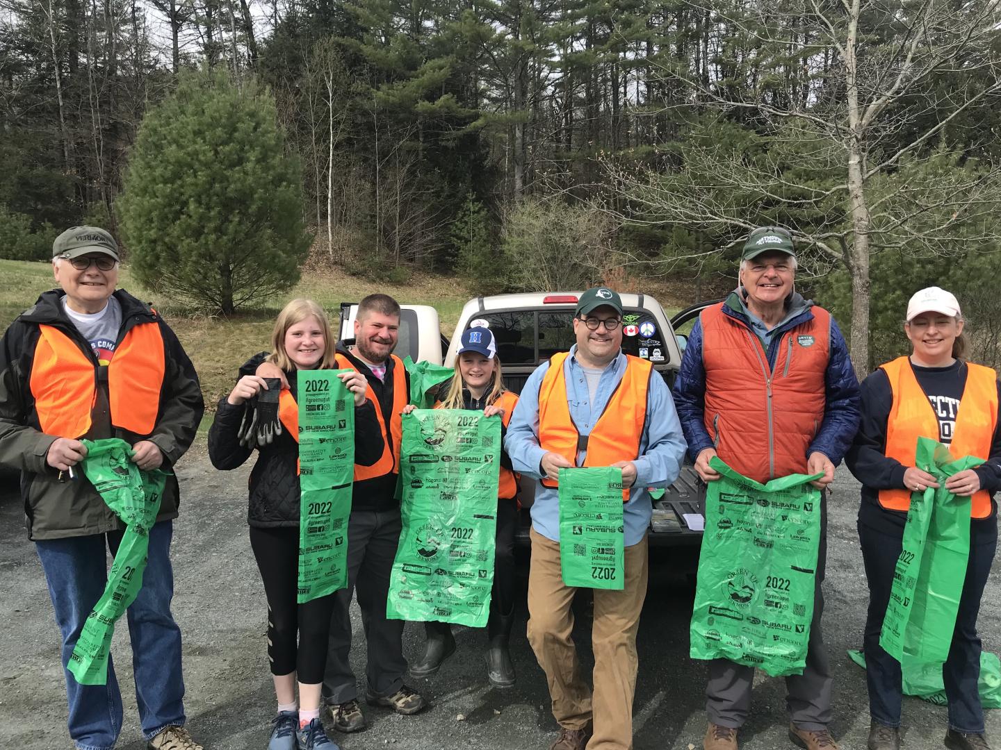 group of volunteers smile with green trash bags 