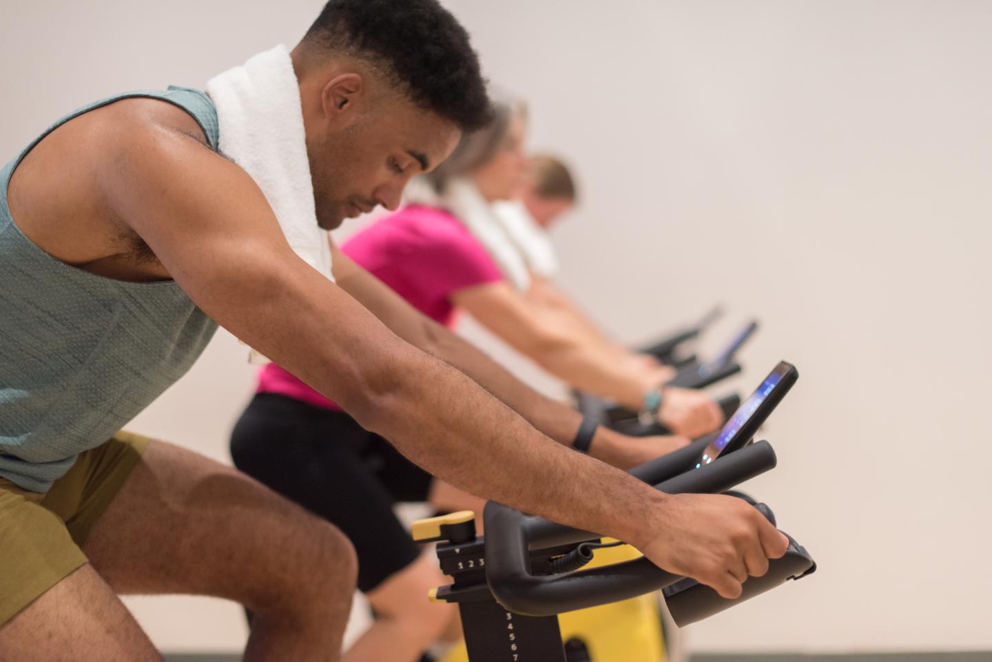 Man on stationary spin bike during indoor cycling class