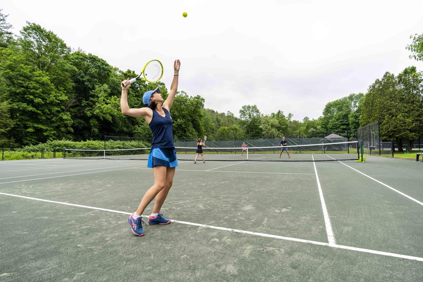 Woman on outdoor tennis court serving ball