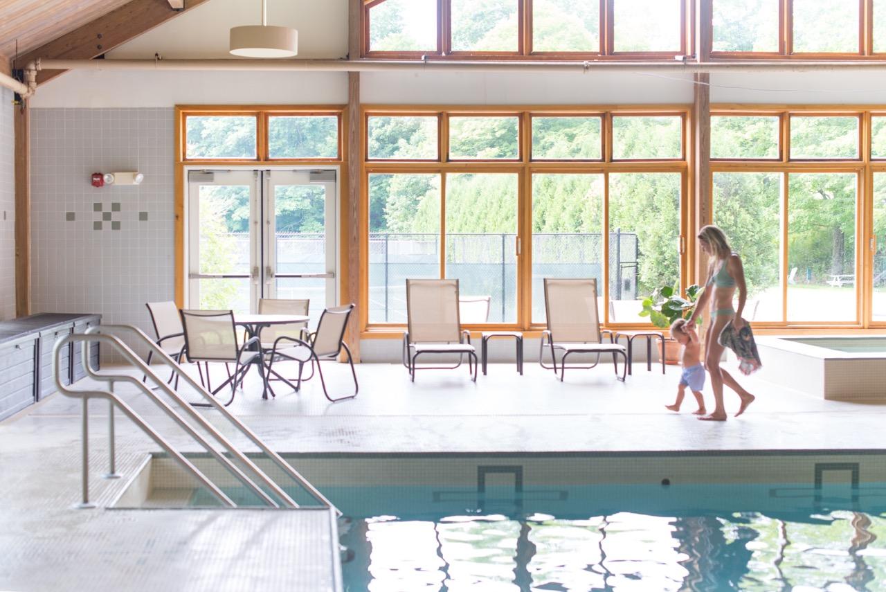 Woman and child walking along the edge of an indoor pool.