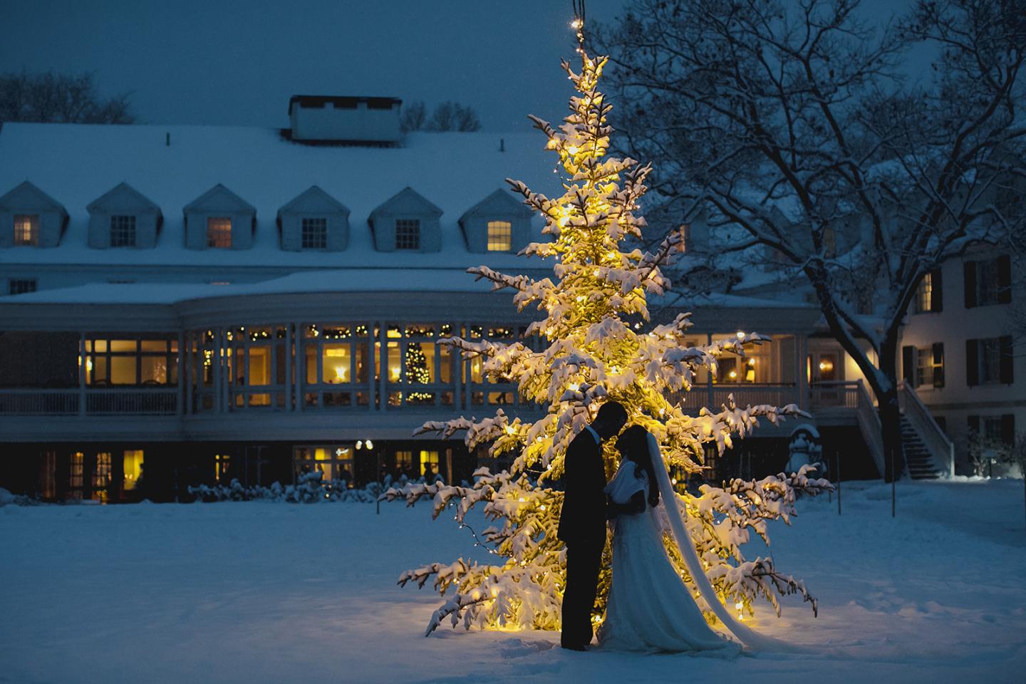 wedding couple in the snow in front of a lit up christmas tree at the Woodstock Inn