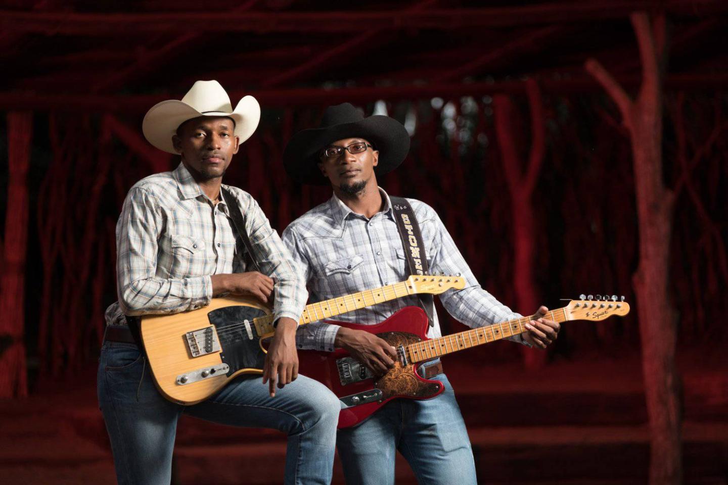 Dusty and Stones holding their guitars looking at the camera