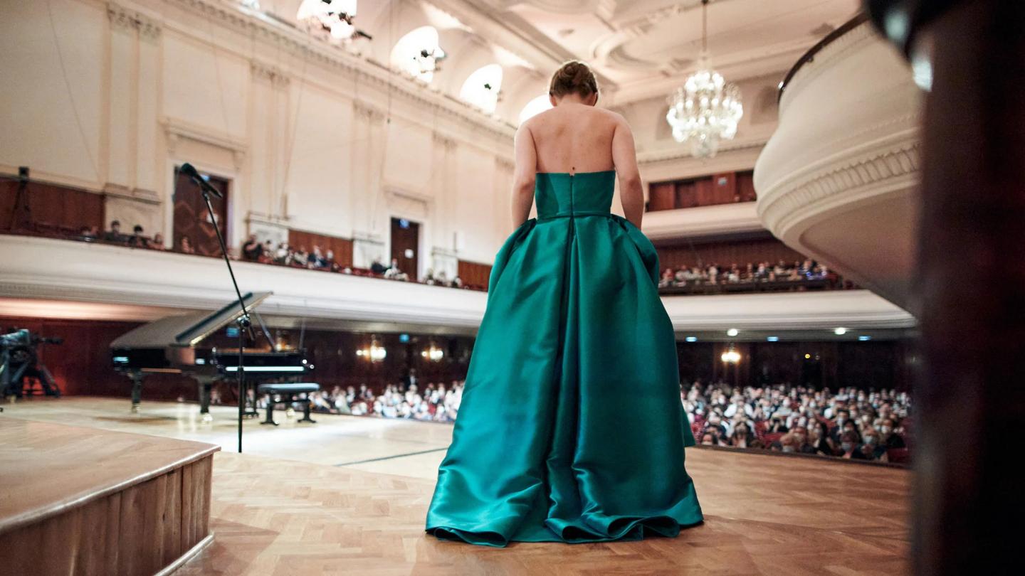 Person in a teal dress bowing on stage