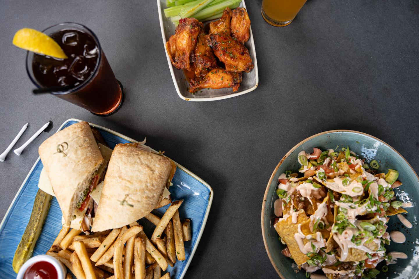 looking down at a table with the turkey club, chicken wings, and nachos