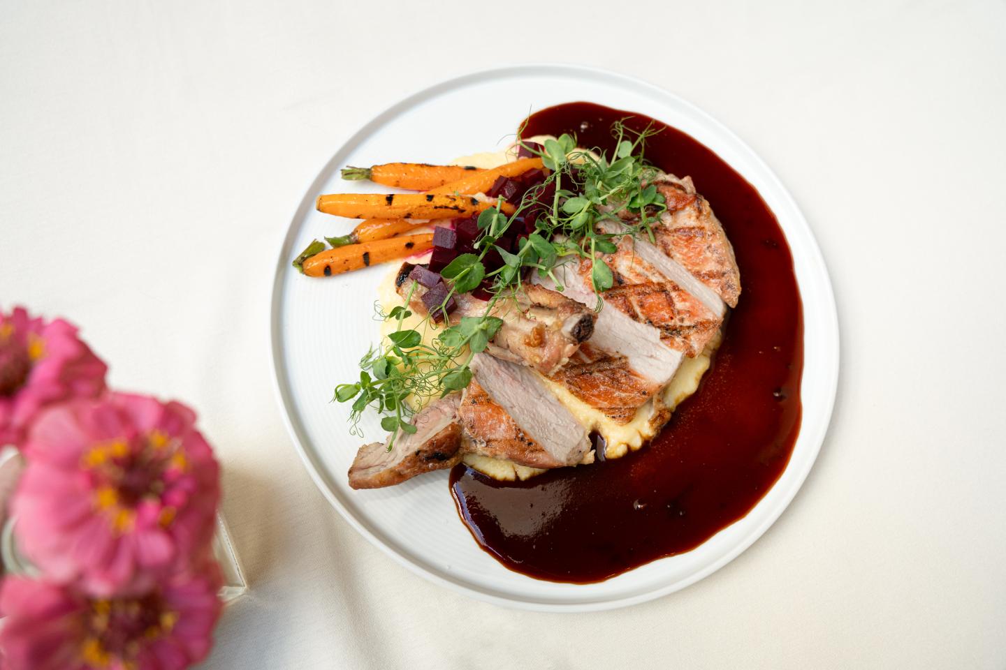 Dinner plate with pork, grilled carrots and a dark burgundy sauce