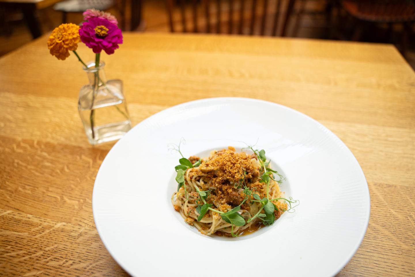 A small plate with pasta topped with breadcrumbs