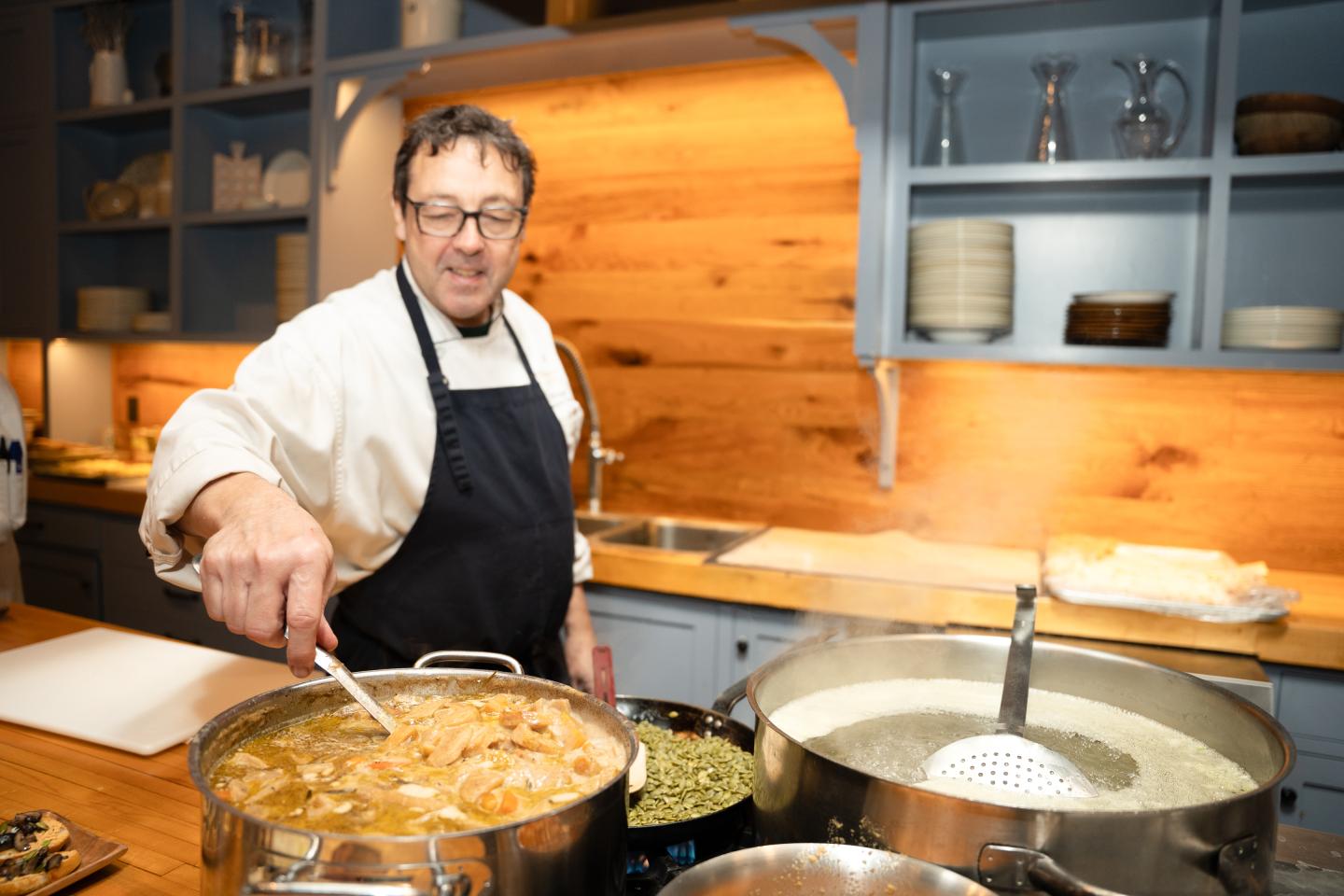 Philippe Niez stirs a large pot of food