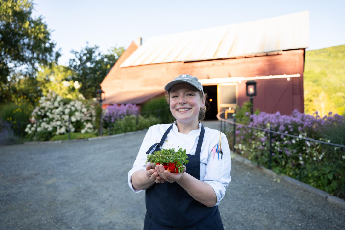 Chef holding fresh picked herbs in front of the red barns