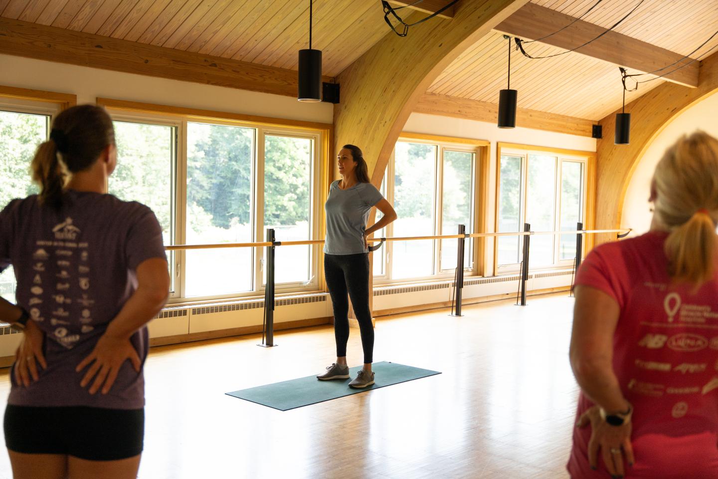 Yoga instructor leading a class in a sunlit studio with wooden beams.