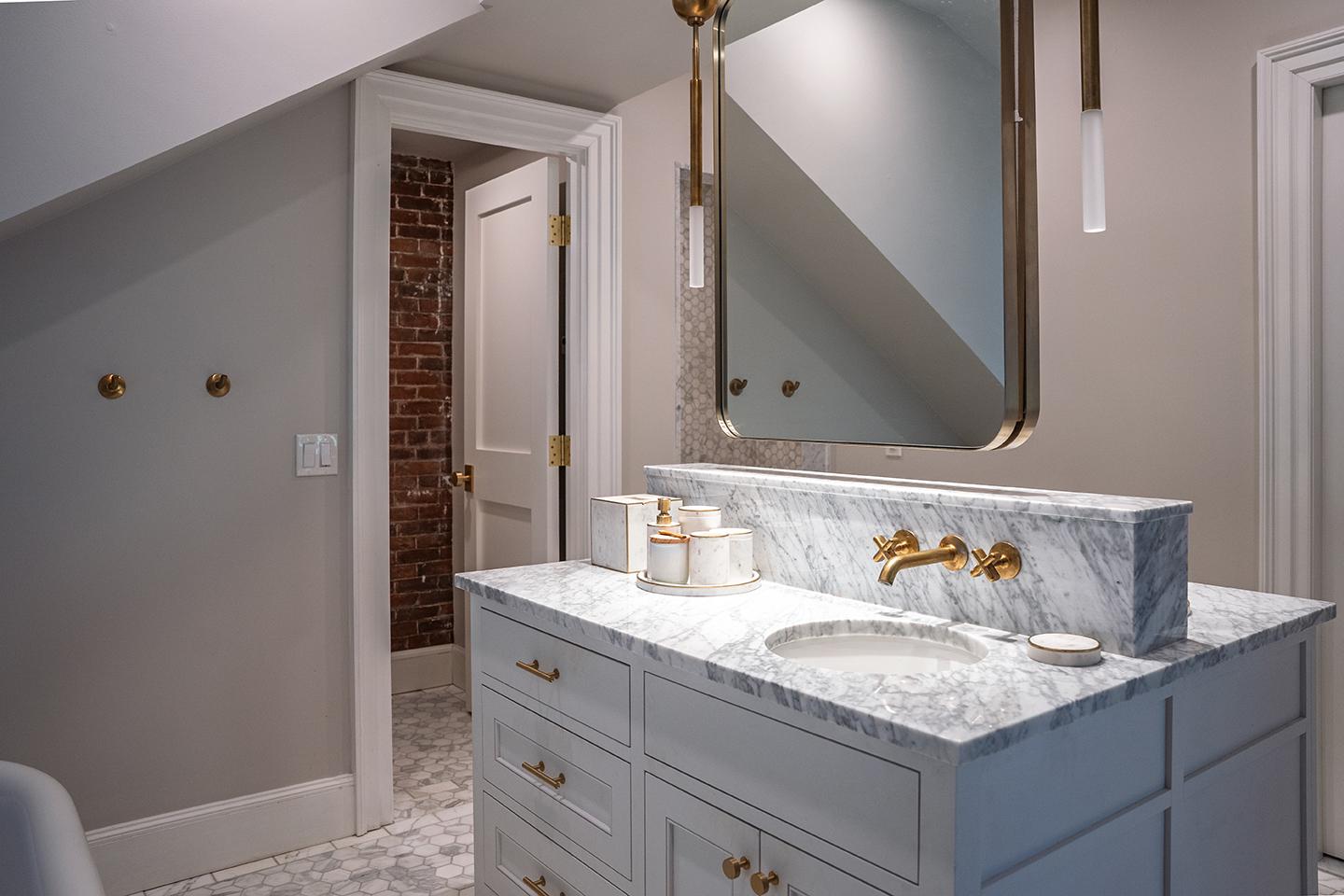 Luxurious bathroom with marble sink, gold fixtures, and a large mirror.