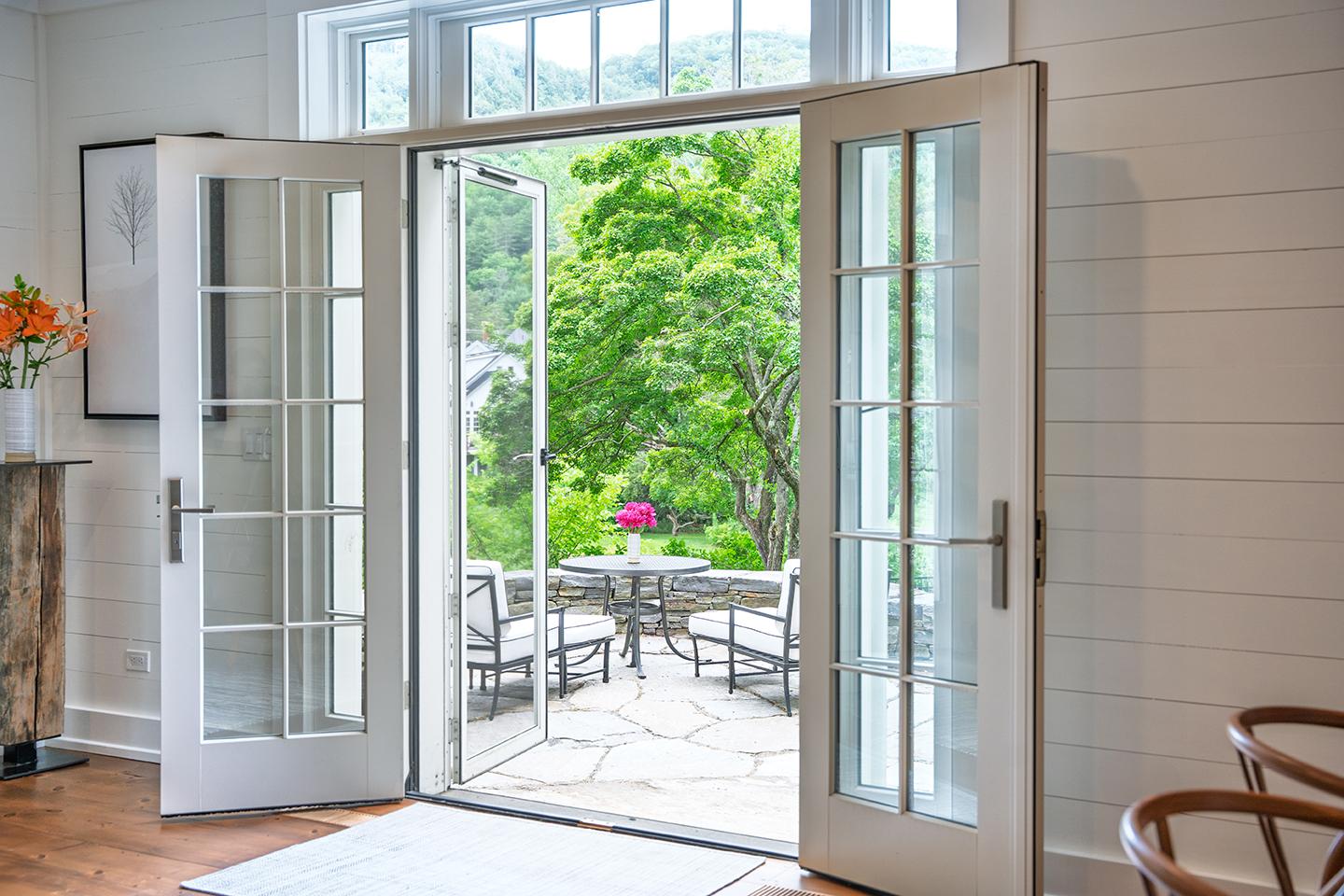 Open patio doors leading to a lush garden with outdoor seating.