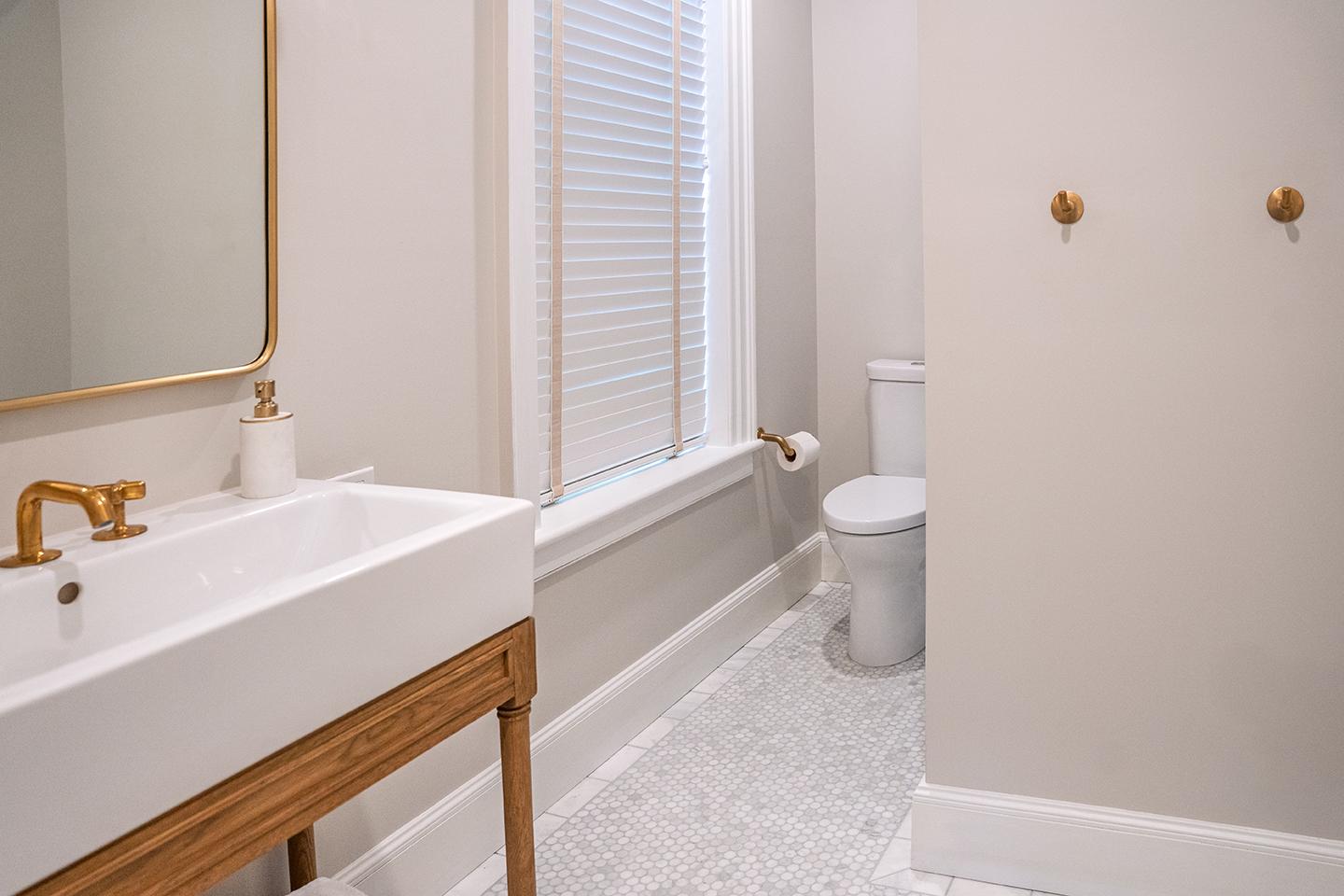 Bright bathroom with a sink, mirror, and toilet.