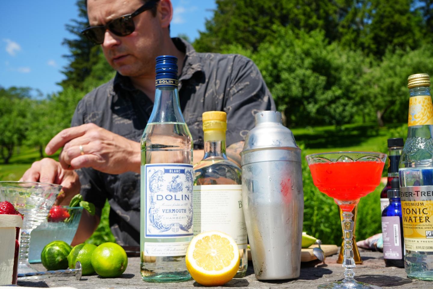 Man preparing cocktails outdoors with various drink ingredients.