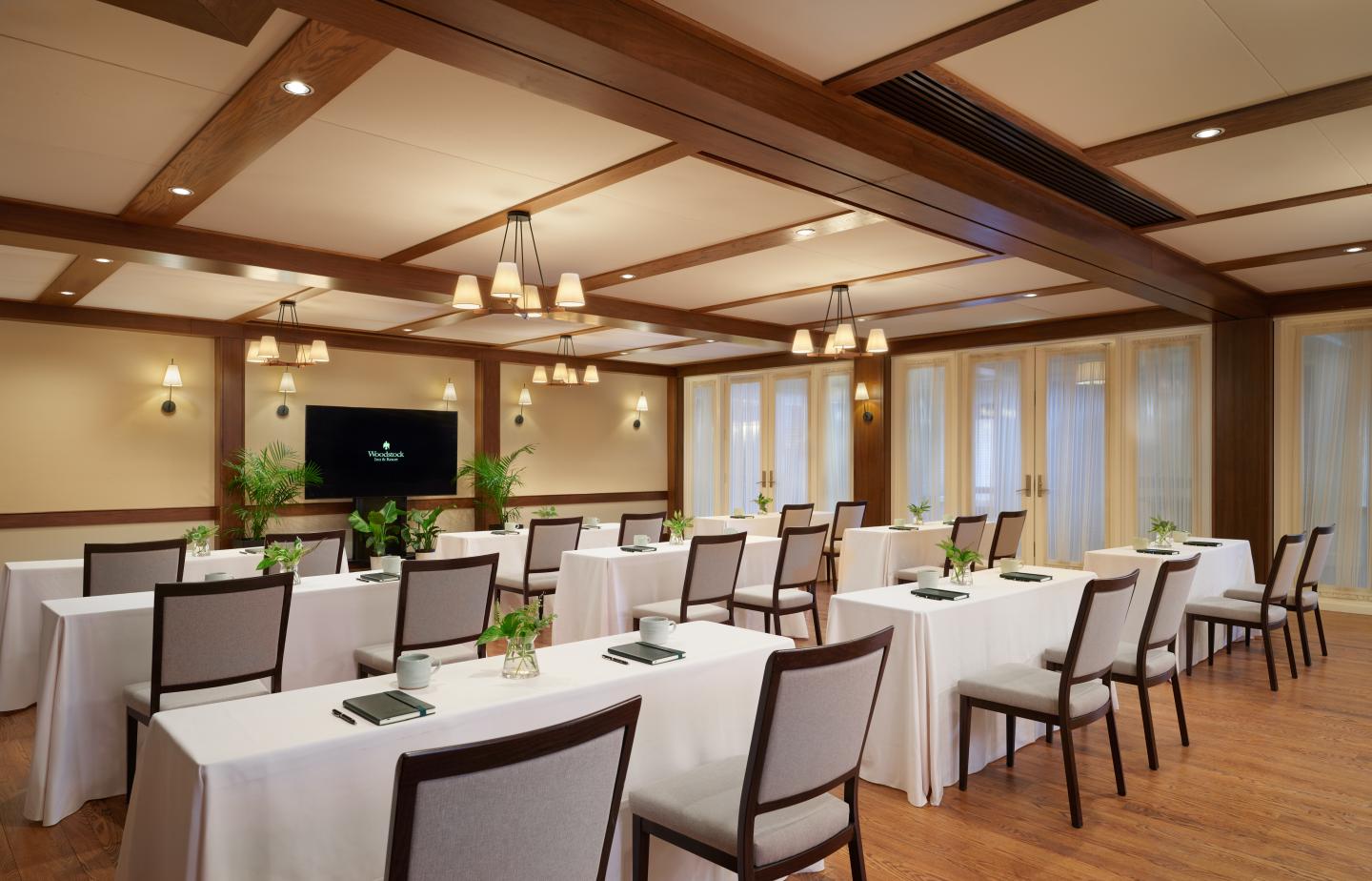 Conference room with arranged tables, chairs, and a wall-mounted display.