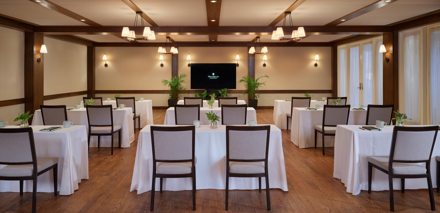 Conference room with arranged tables and chairs, a TV screen, and soft lighting.