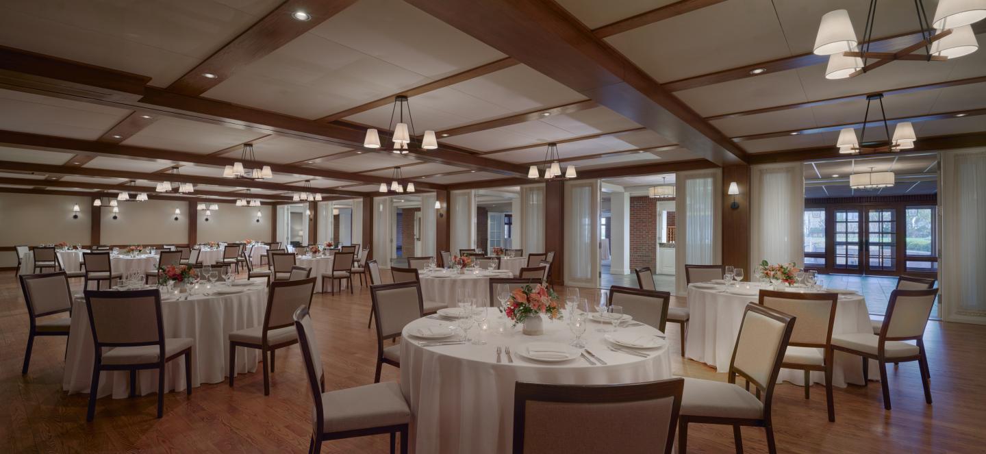 Spacious banquet hall with round tables and elegant lighting.