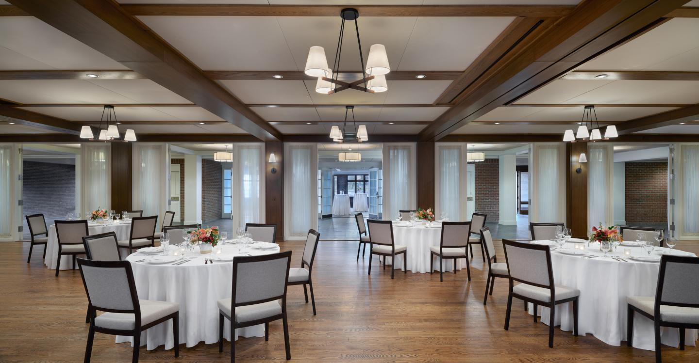 Elegant banquet hall with round tables, white tablecloths, and soft lighting.
