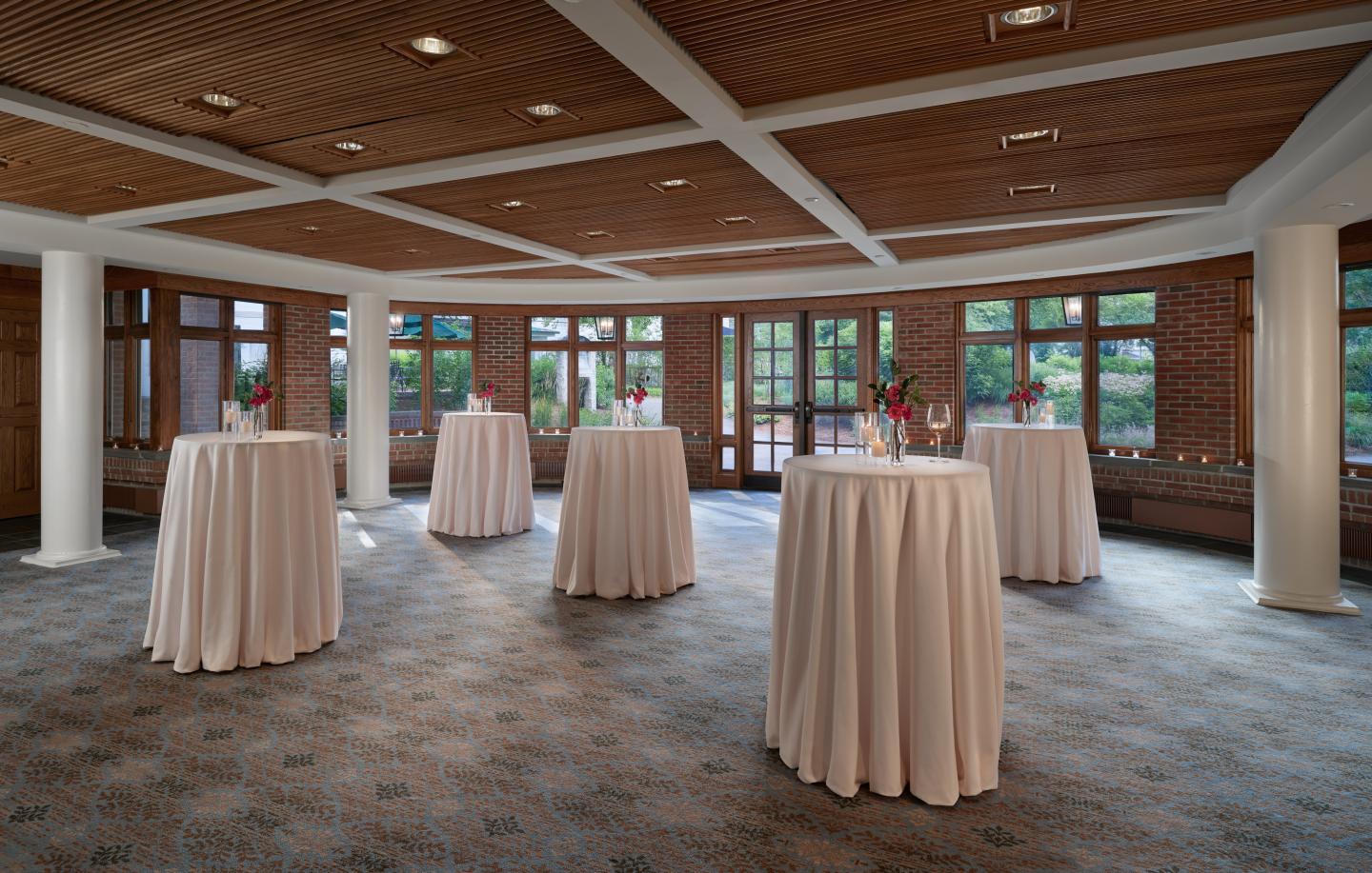Elegantly decorated event space with round tables and white tablecloths.