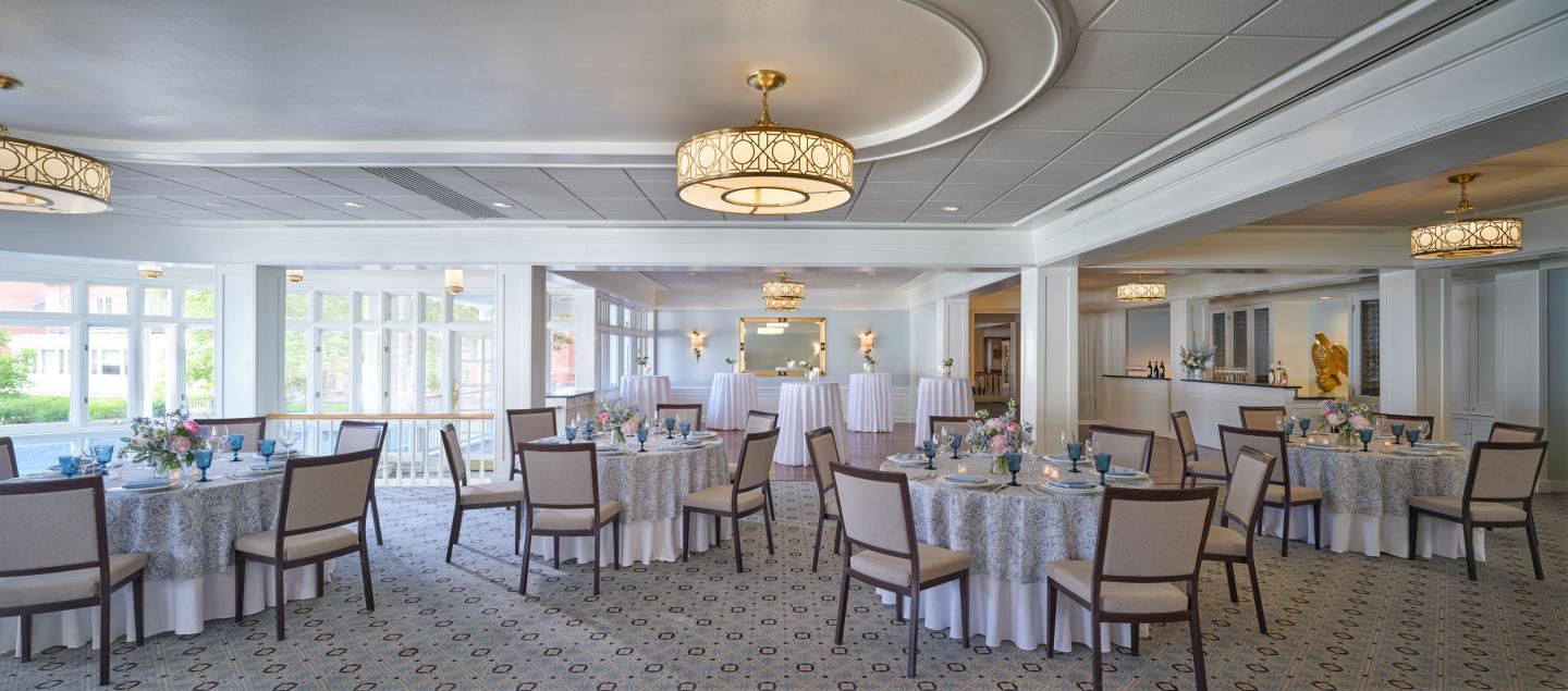 Elegant banquet hall with round tables and chandeliers, set for an event.