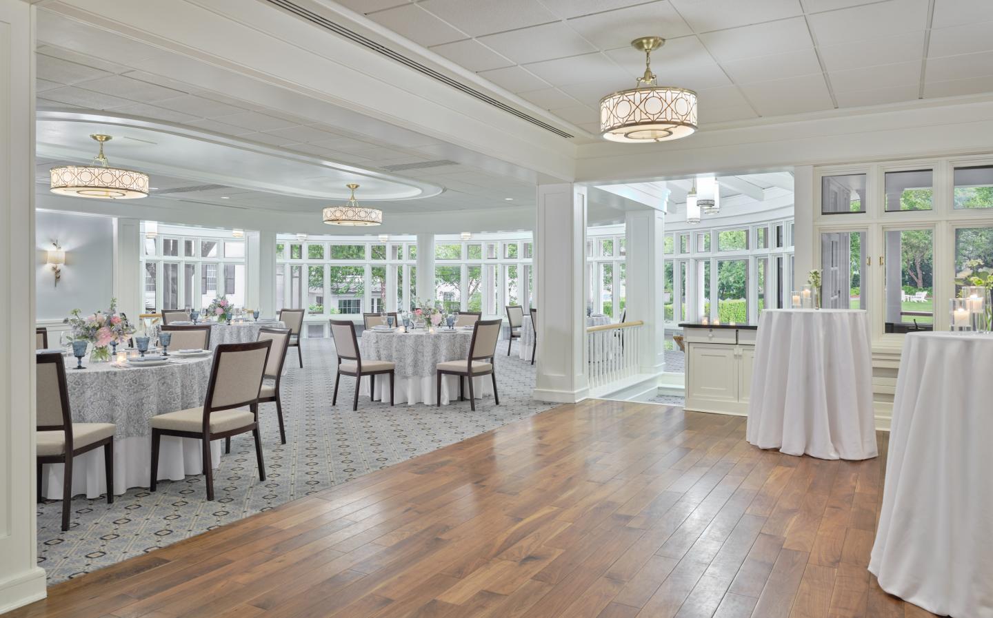 Spacious, elegant banquet hall with round tables and large windows.
