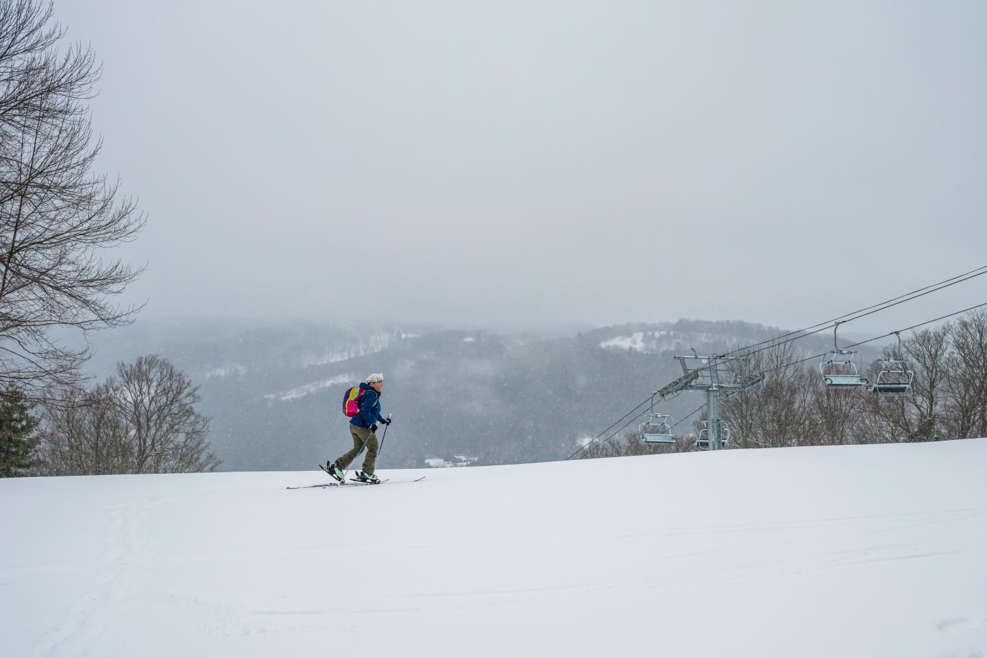 Skier on a snowy slope with misty mountains in the background.
