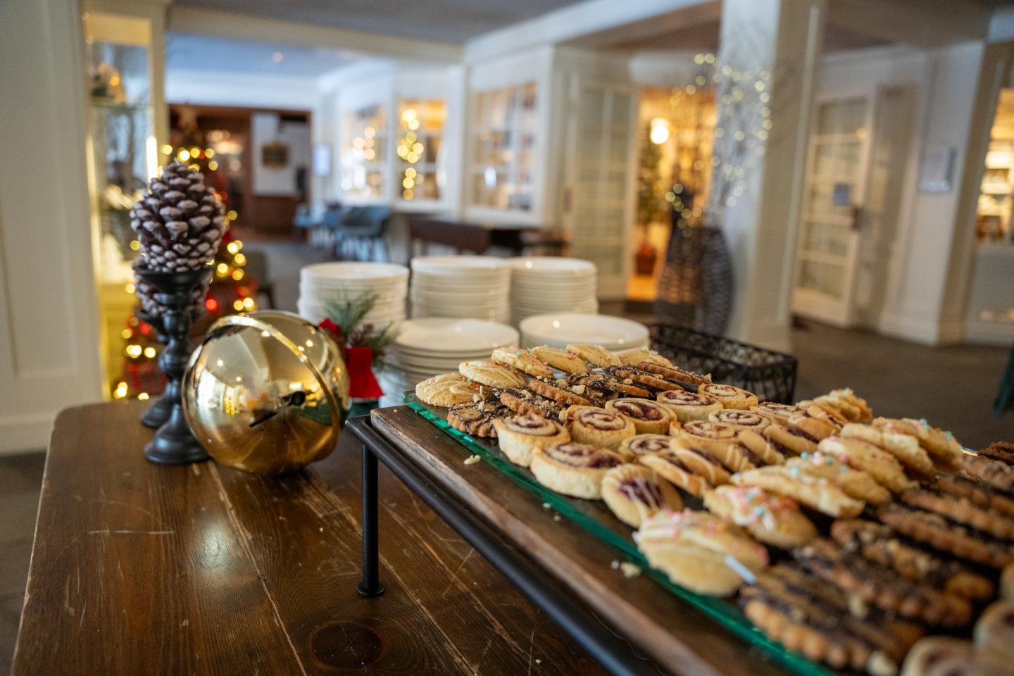 Festive buffet with assorted cookies and plates in a decorated room.
