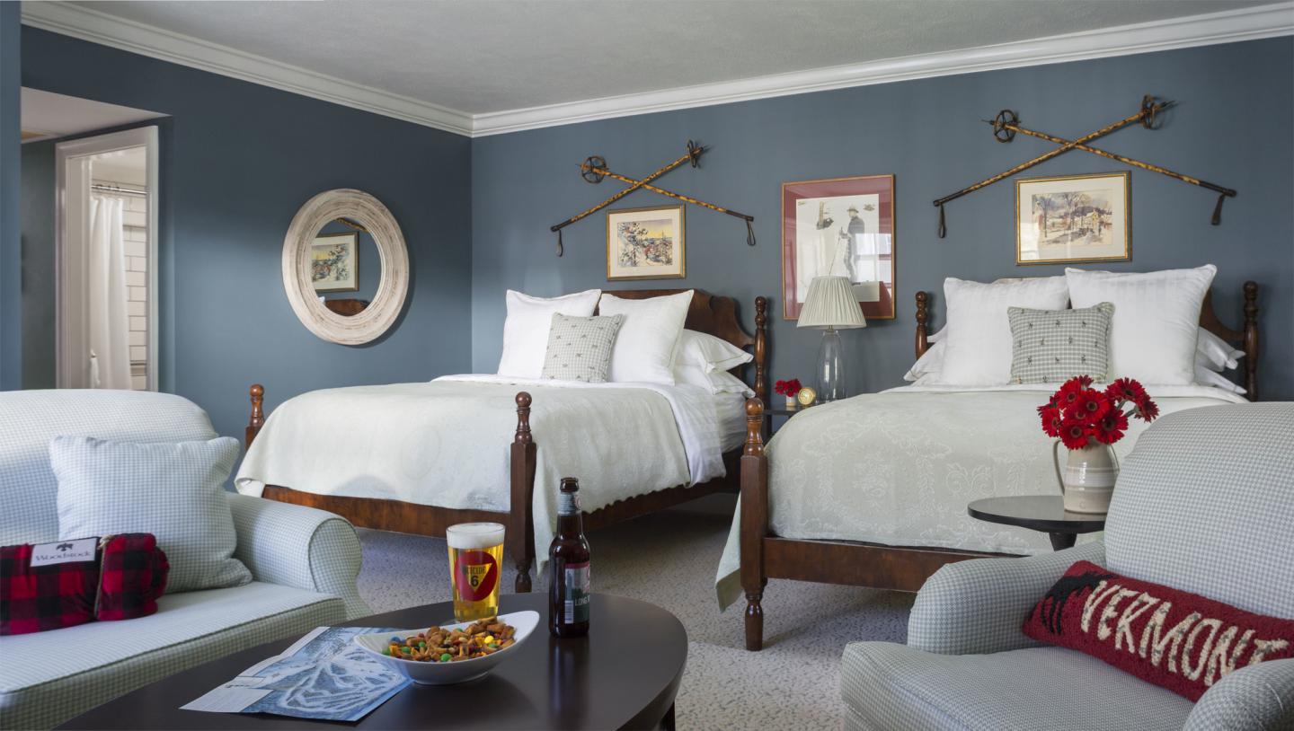 Elegant hotel room with two beds, blue walls, and a cozy sofa.