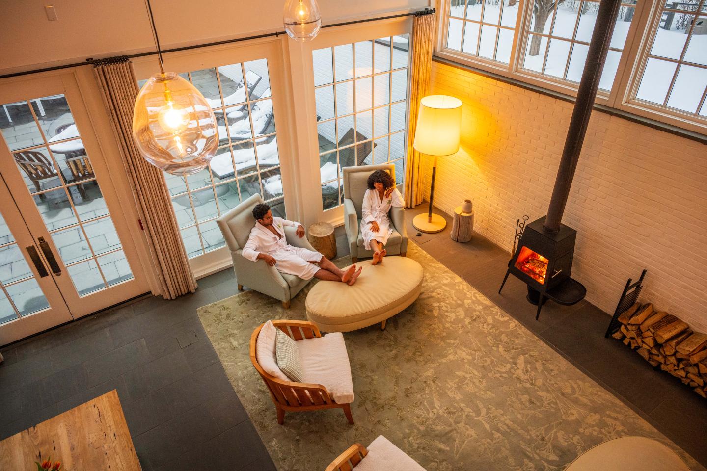 Spa lounge with fireplace, two people in robes relaxing on chairs.