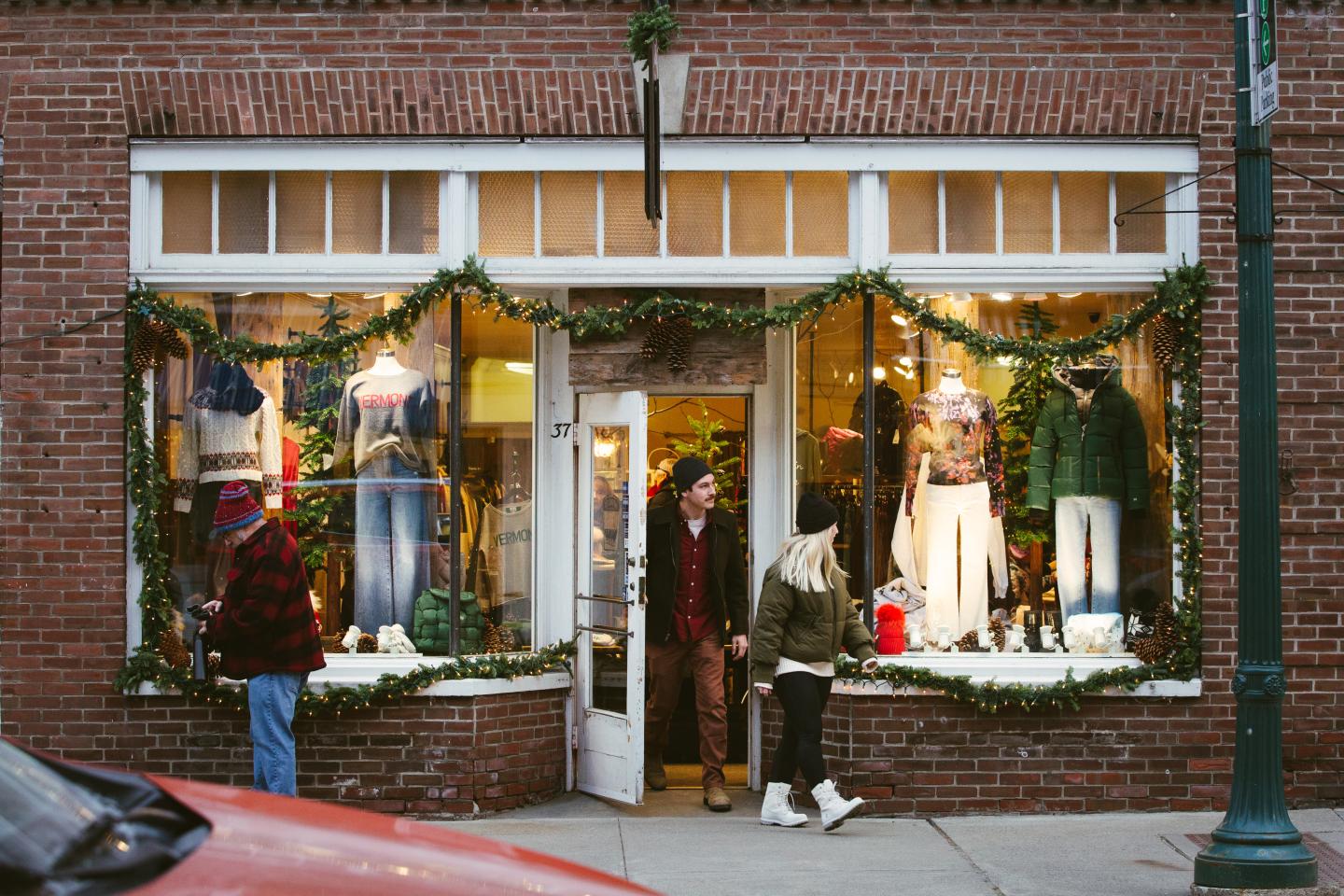 Boutique storefront with winter decor and two people entering.