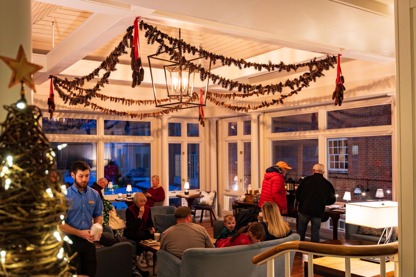 Cozy lounge with holiday decorations and people gathered in conversation.