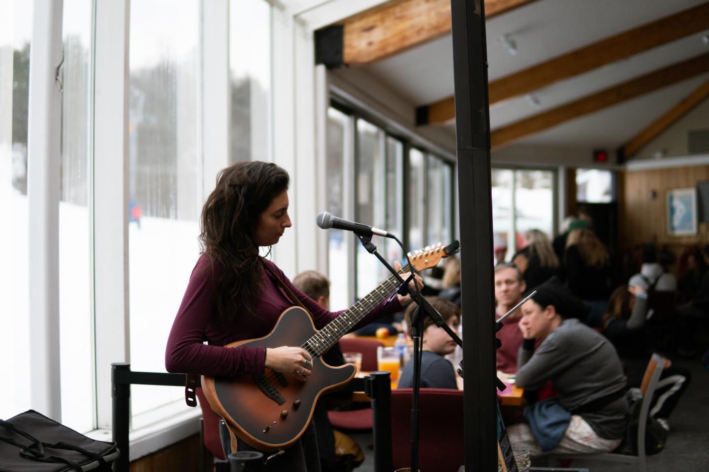 Musician playing guitar and singing in a cozy café.