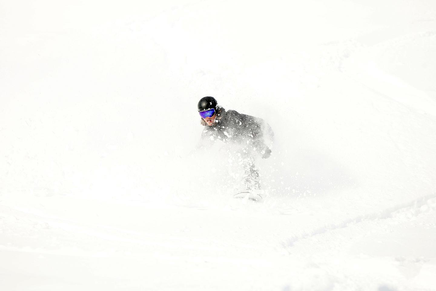 Snowboarder glides through fresh powder on a snowy slope.