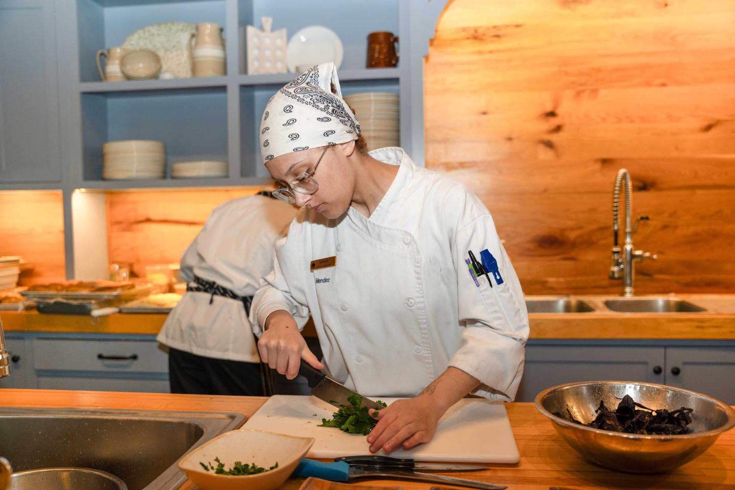 Line Cook chopping herbs in a kitchen