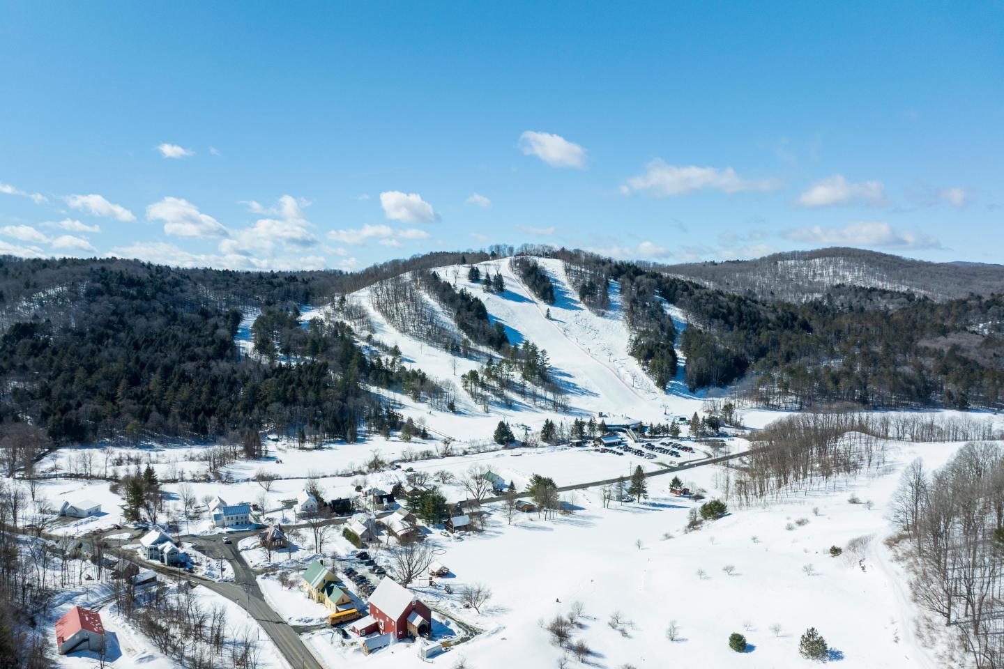 Snow-covered village and ski slopes under a clear blue sky.