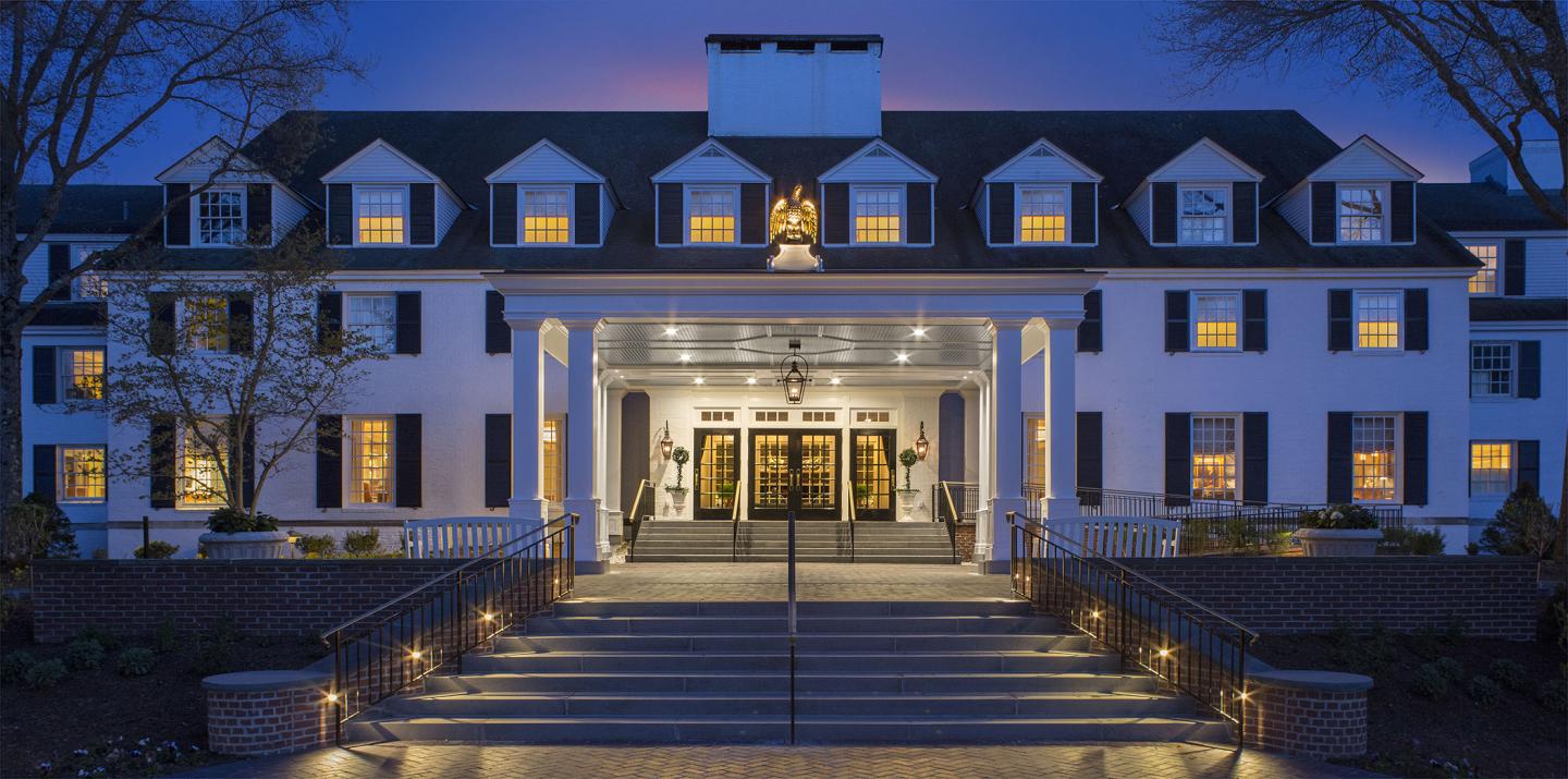Grand hotel entrance lit up at dusk with steps and lanterns.