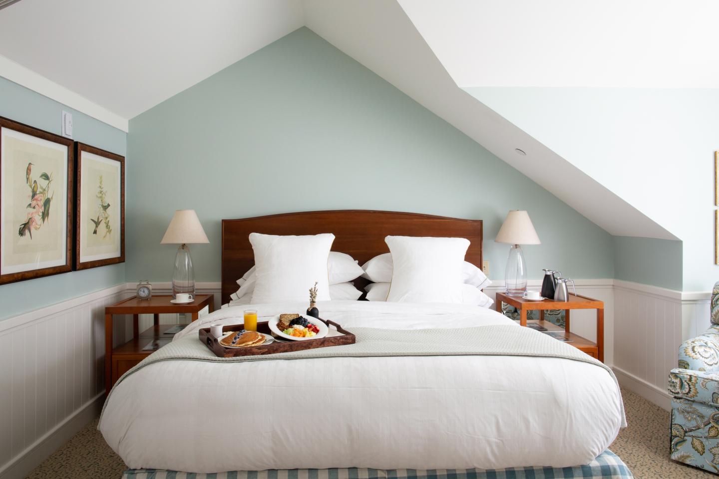 Cozy bedroom with a tray of breakfast on a neatly made bed.