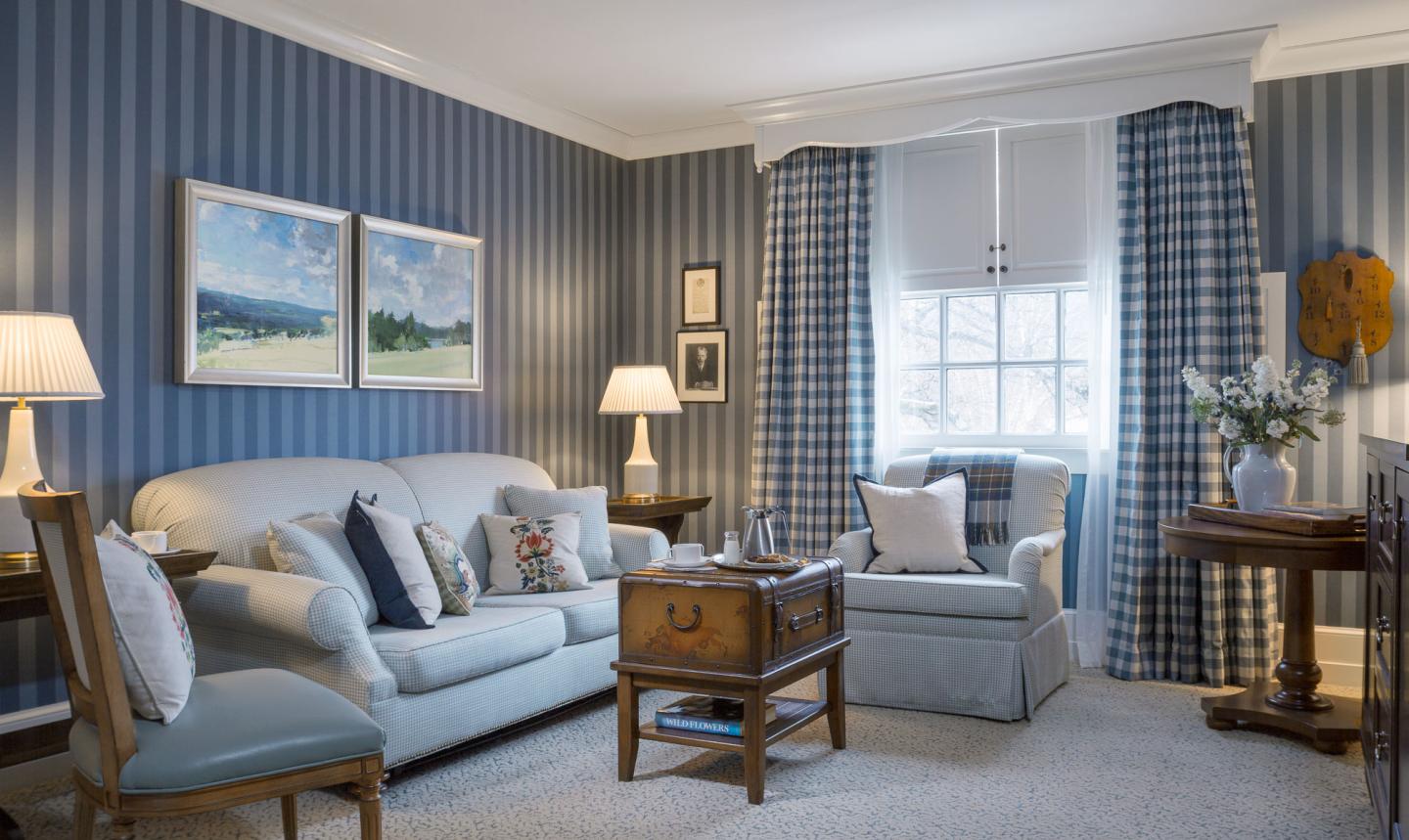 Cozy living room with blue-striped walls, sofa, and armchair.