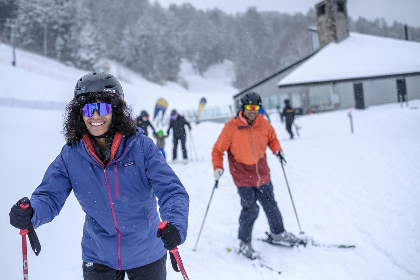 Skiers in colorful jackets enjoying a snowy slope near S6 base lodge..