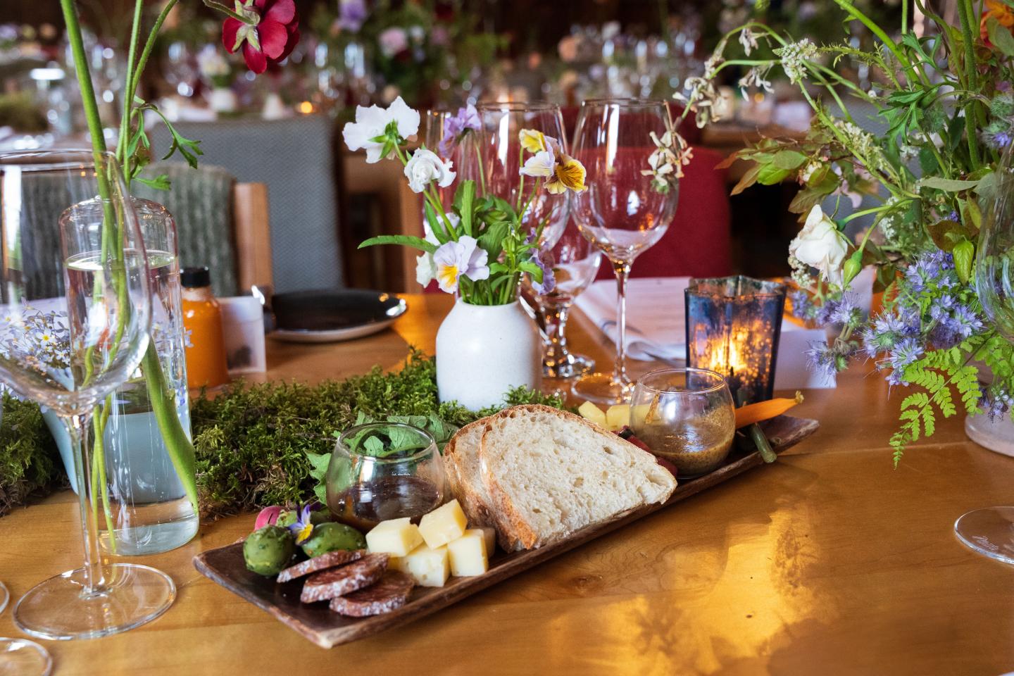 Cheese and bread platter on an elegantly decorated table with flowers.