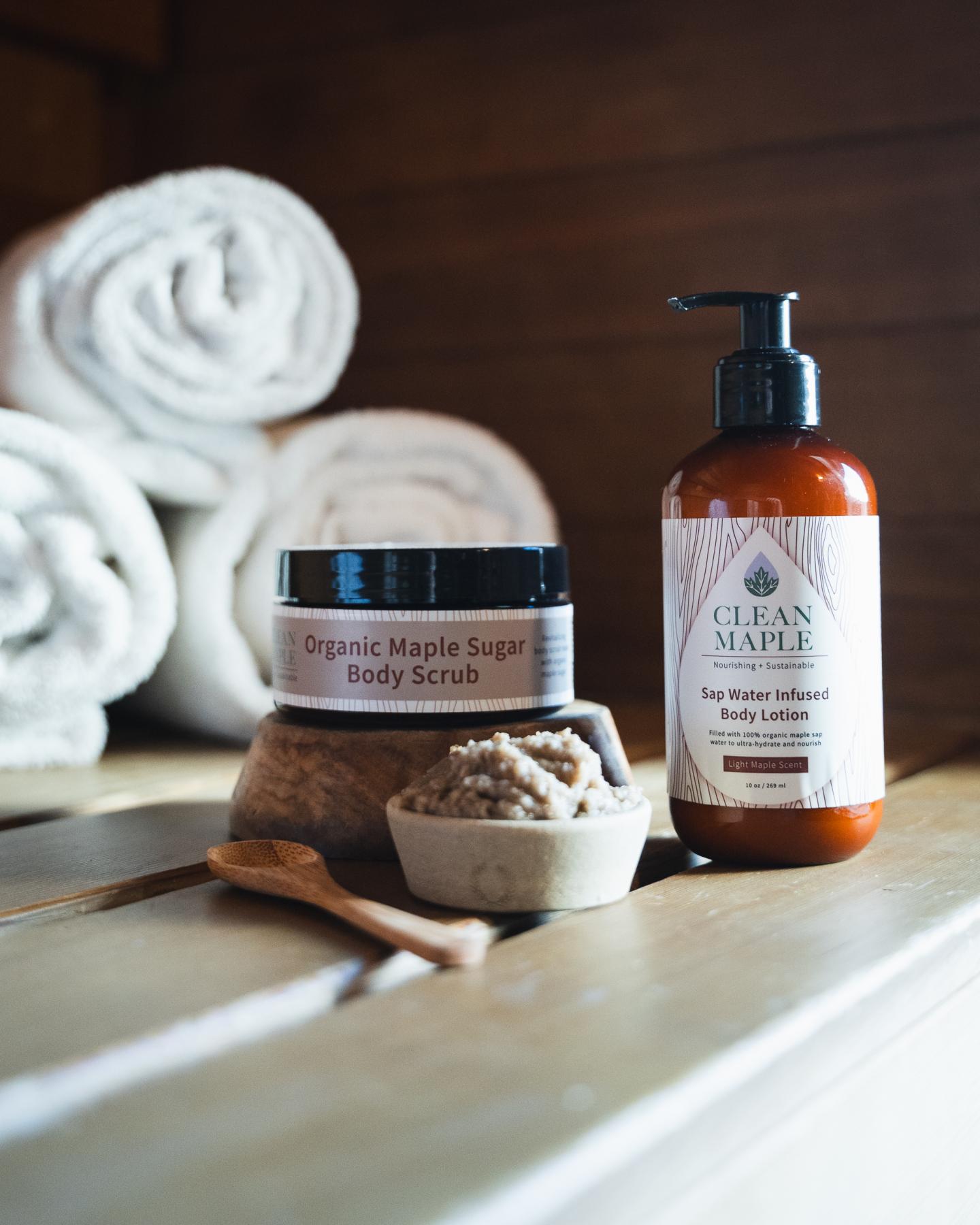 Body scrub and lotion bottles on a wooden shelf with rolled towels.