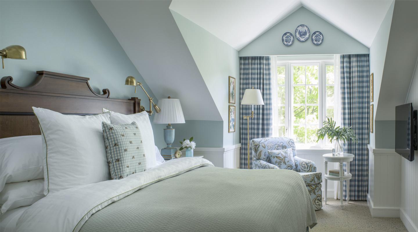 Cozy bedroom with blue accents, white bedding, and a window seat.