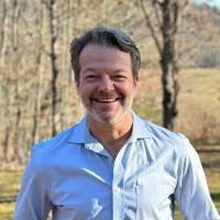 Richard Enderlin in a blue shirt outdoors in a park with trees.