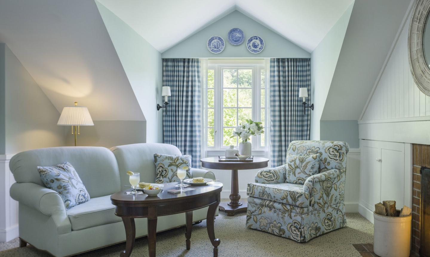  Cozy living room with blue sofa, floral armchair, and checkered curtains.