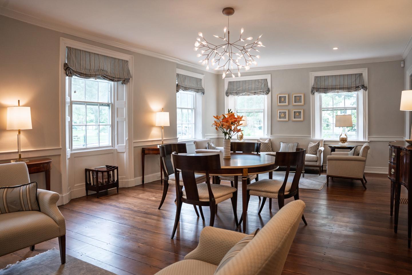 Elegant dining room with chandelier, wooden table, and upholstered chairs.